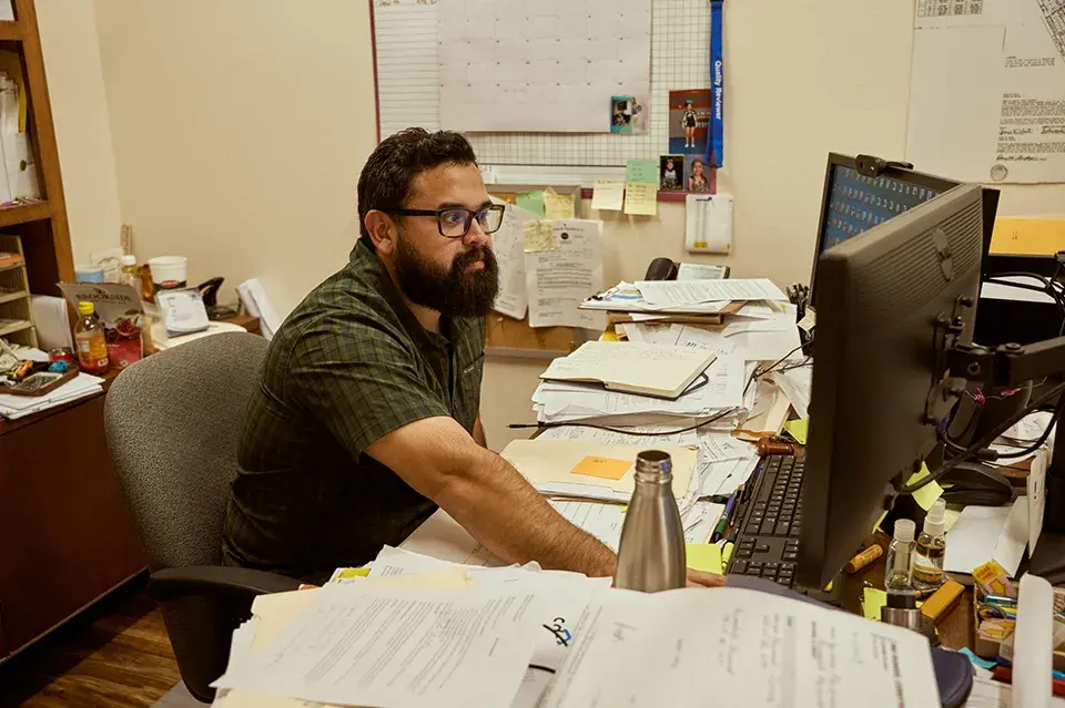 Man sitting at a desk in front of a computer and papers
