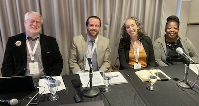 Four people smiling at conference panel table