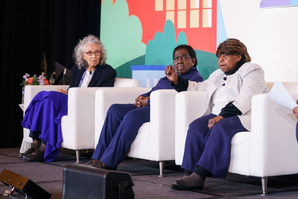 Three senior women seated on a stage