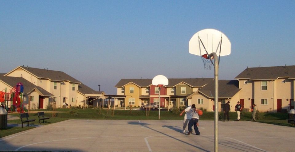 People playing on a basketball court with apartment buildings in background