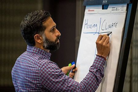 A man writes on an easel paper pad