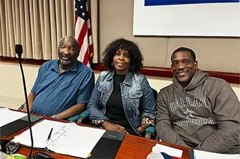 Three people seated at a conference table