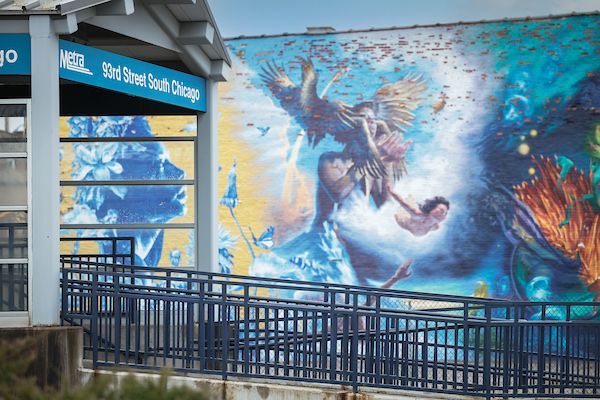 Ramped entrance to the train station with a multi-colored mural in the background.