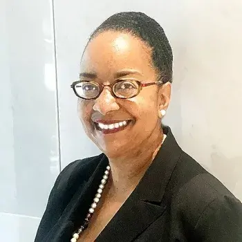 Headshot of an African American woman in professional attire and glasses smiling at the camera.
