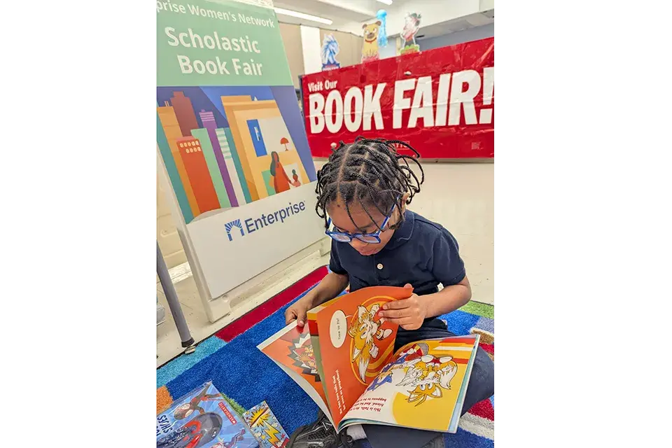 A young student reads a book at the Enterprise Scholastic Book Fair