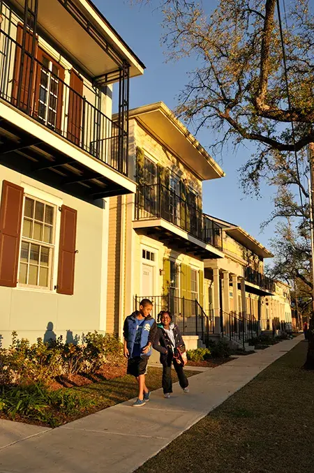 Two boys on a sidewalk lined with yellow two-story homes