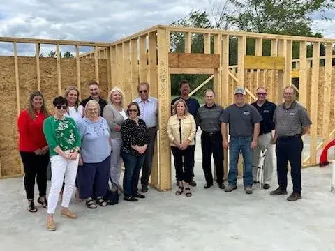 Smiling people standing in front of wooden frame for a home