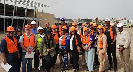 A group of people wearing orange hard hats, ready to take a tour