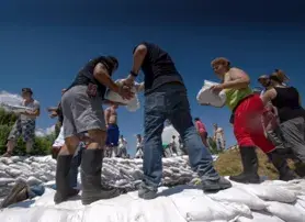 Volunteers distribute items to people in line at a disaster relief site
