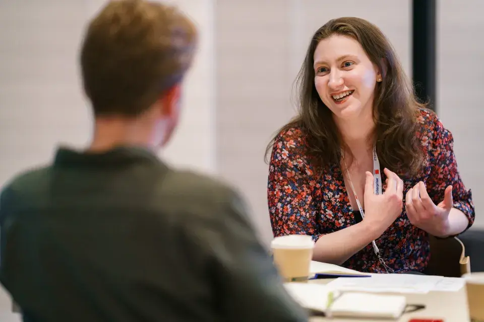 A woman sitting at a desk talking to a person on the other side