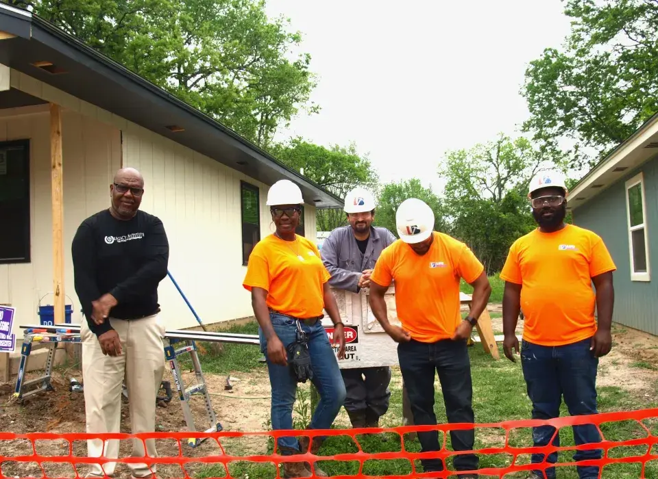 Construction workers in bright orange shirts and hardhats on job site