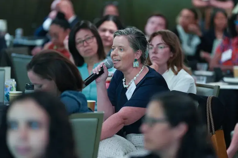 Woman speaking into a microphone in convening room