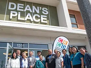A group of people standing together in front of the entrance to Dean's Place