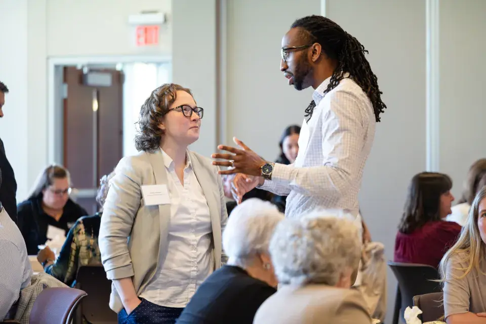 Two professionals at the convening networking and speaking with another.