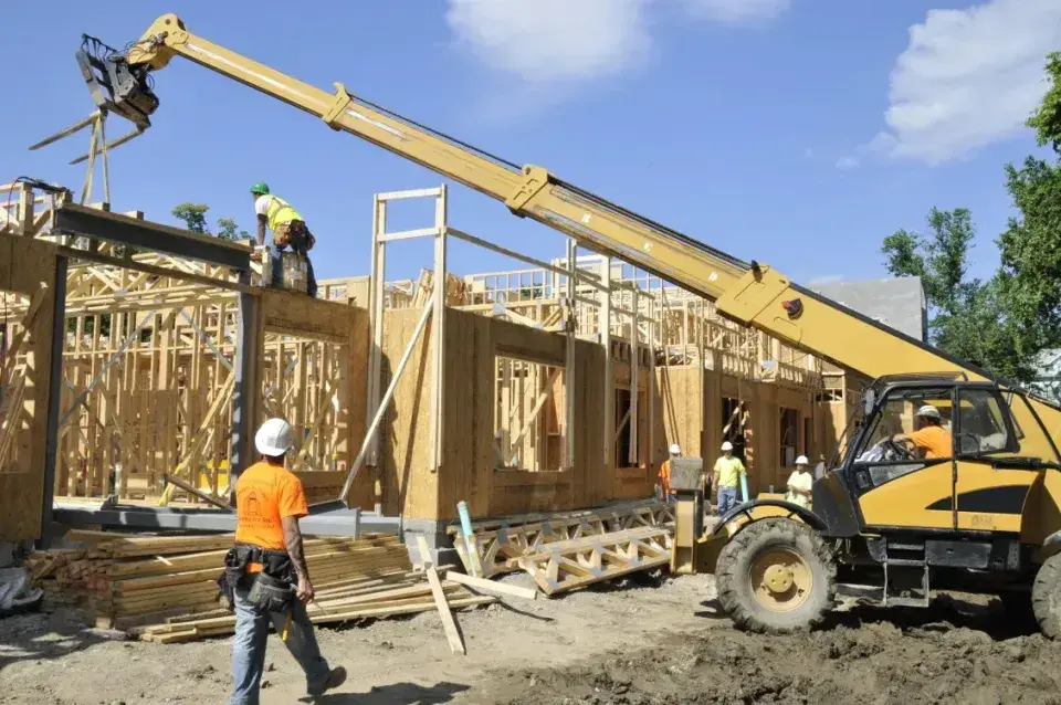 Irvington Mews under construction with a crane operator, a worker on the roof, and a worker observing on the ground
