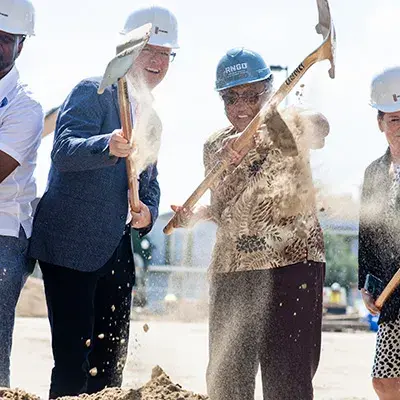 Shaun Donovan with guests wearing hard hats and holding shovels at a groundbreaking ceremony