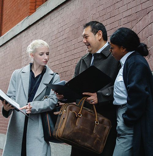 Three people outside looking at paperwork