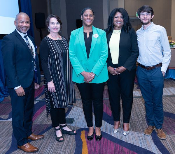 Five people in business attire standing in a row