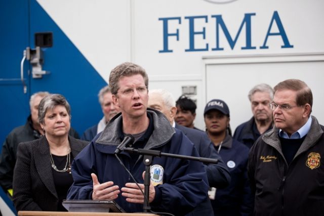 Shaun Donovan, Incoming CEO and President, speaks at a podium in front of a FEMA truck with people behind him.