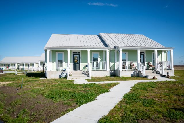 Small one-story duplex apartment structure with sloped roof and a walkway and grass in the foreground.