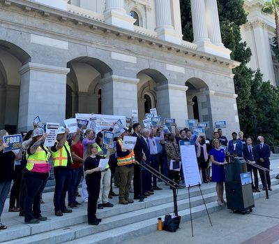 People holding signs supporting ACA1 in front of California Capitol