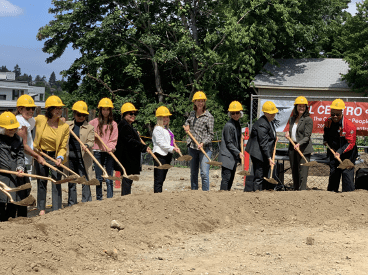 People in hardhats with shovels at groundbreaking ceremony