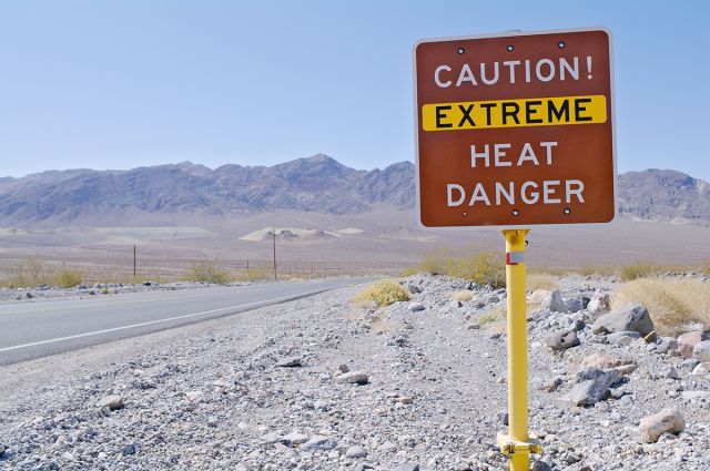A sign that says: "Caution! Extreme heat danger."  The sign is on the side of a road.