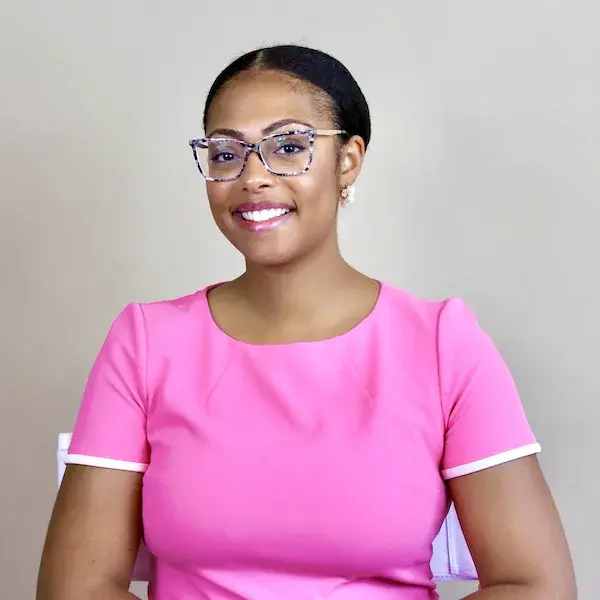 Smiling woman wearing glasses and a pink dress