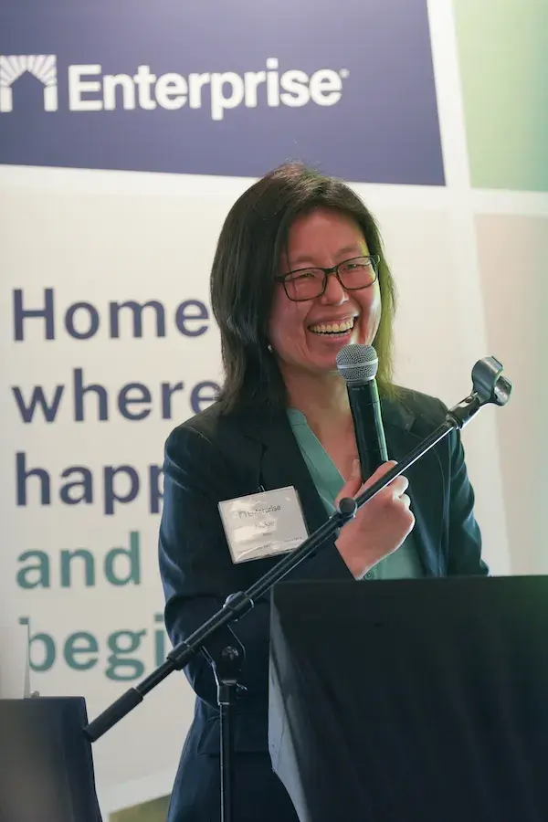 Smiling woman speaking into microphone behind podium