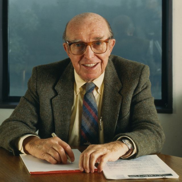 Jim Rouse sitting at a desk signing papers