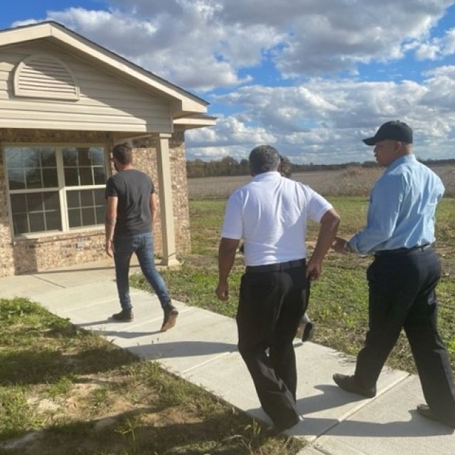 Three men walk up to a house