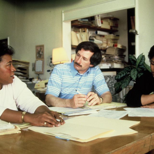 white male and two Black women sitting at a table in discussion