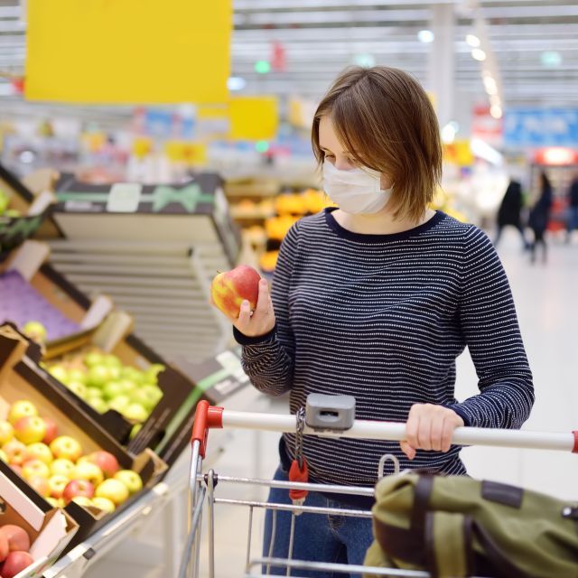Woman with mask shopping in fruit section of grocery store