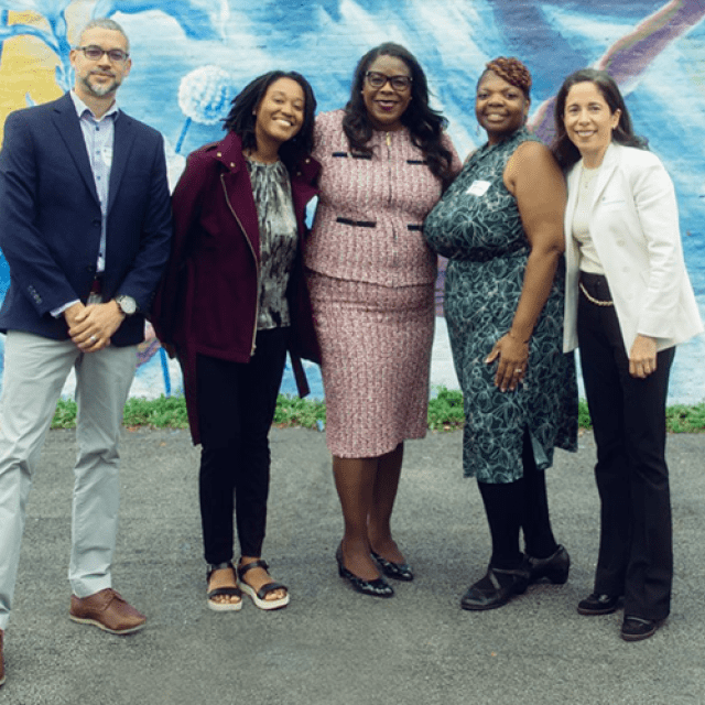 Four women and one man standing in front of a mural