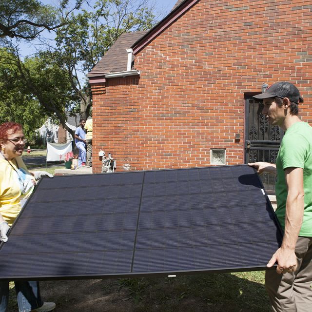 Two people carrying a solar panel