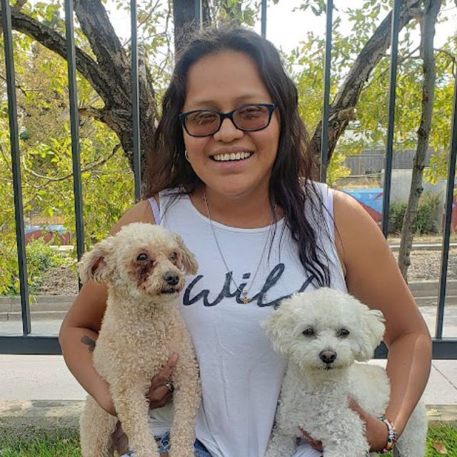 A woman holding two dogs and smiling
