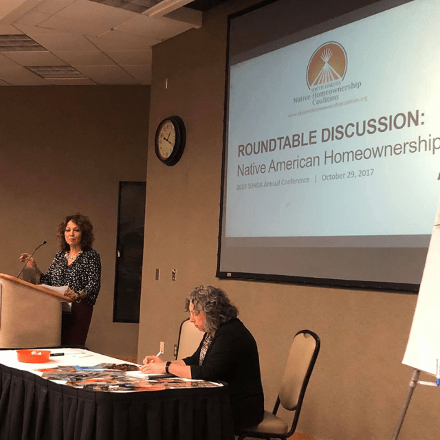 A woman speaking at a podium while giving a presentation