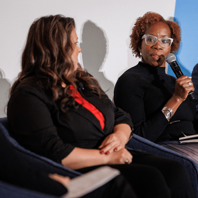A woman speaking into a microphone sitting between a man and another woman