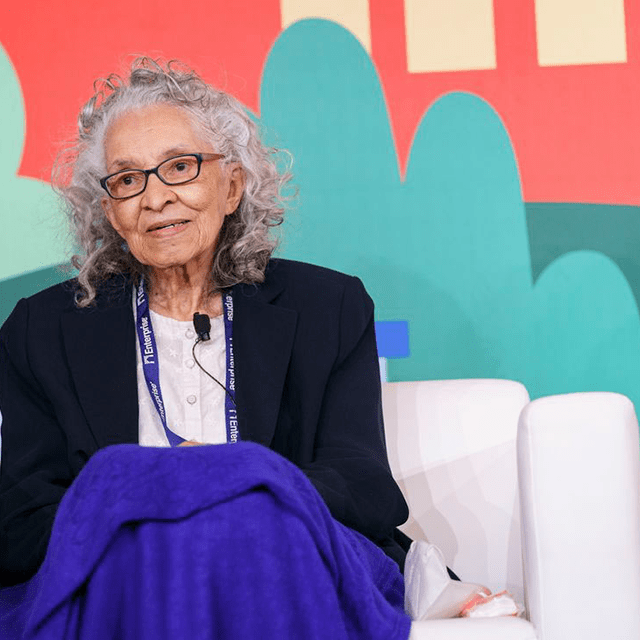 A woman with gray hair sitting in a chair speaking