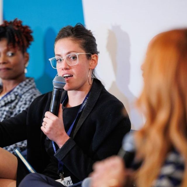 Julianna Stuart of Preservation of Affordable Housing speaks into a microphone as part of a panel