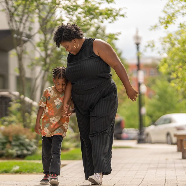 A mother and her son walking down the street smiling