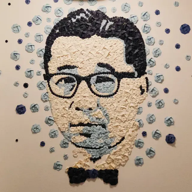 A blue and tan origami portrait of Gordon Hirabayashi, a Japanese American civil rights activist