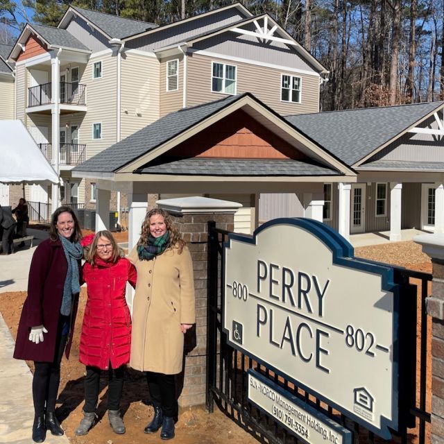 Three Women Standing in Front of the Perry Place Apartment Building Sign