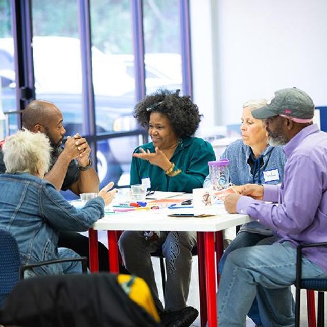 Five people sit and talk at a table 