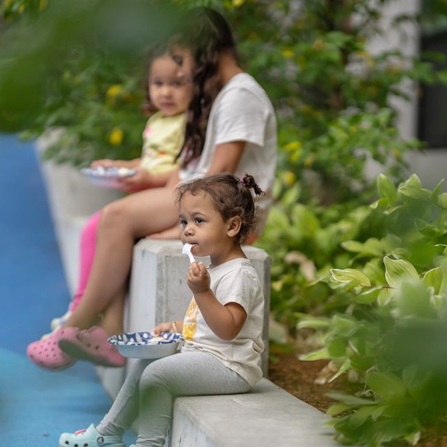Three little girls outside sitting, eating and talking