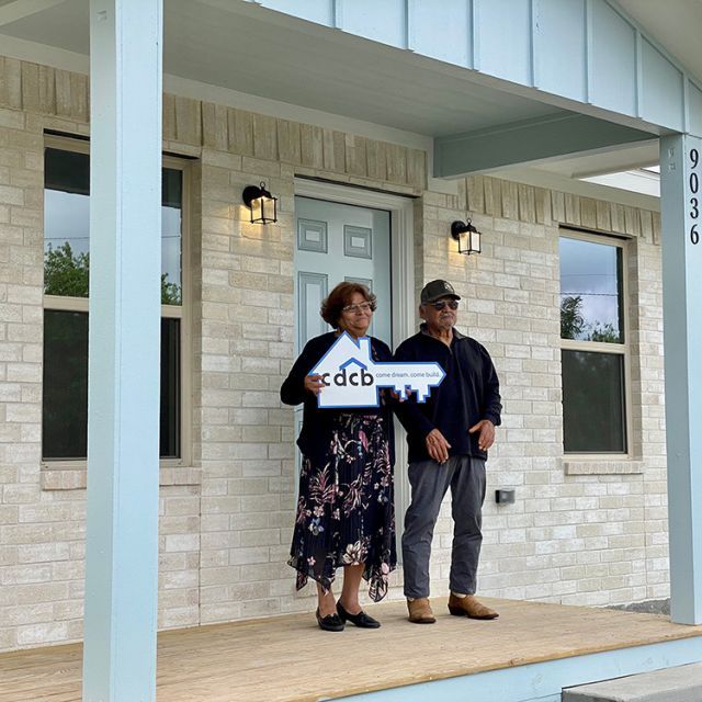 A couple standing on the porch of their new home smiling