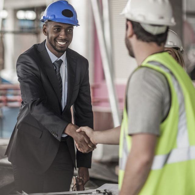 Man in business suit with blue construction hat shaking hands