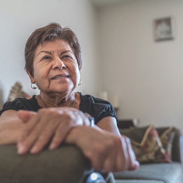 Woman with hands folded sitting on couch