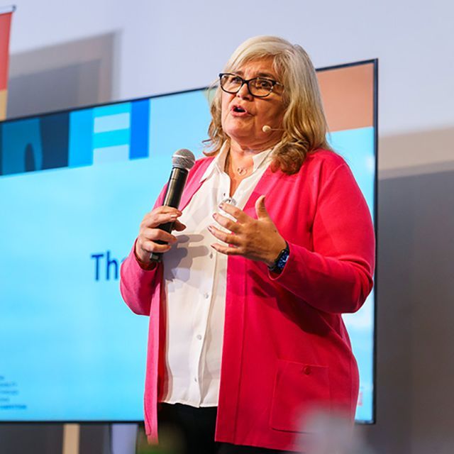 A woman standing talking into a microphone