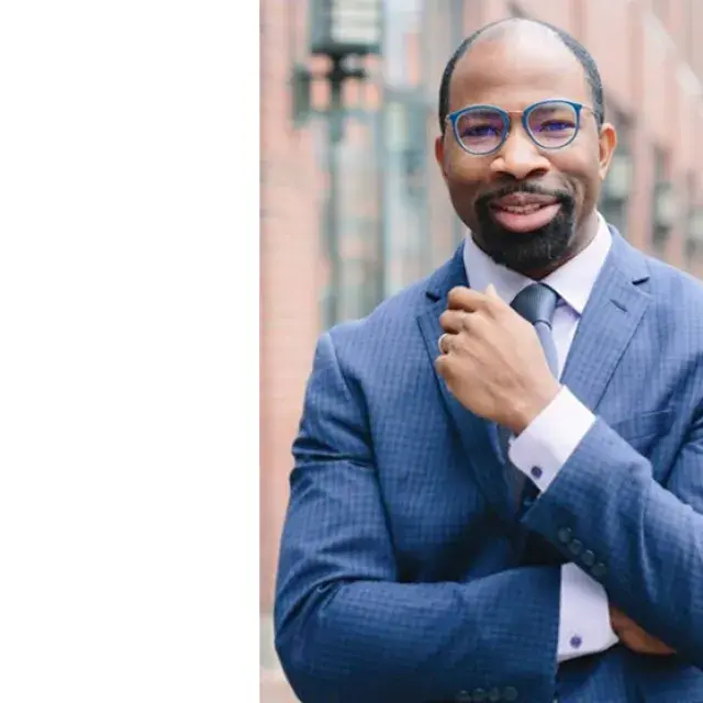 Man wearing glasses stands with arms crossed